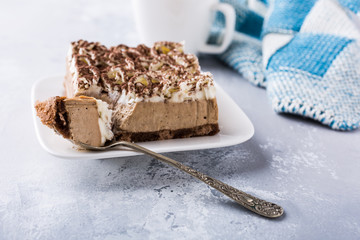 Portion of semifreddo cake, delicious chocolate dessert on white plate with cup of coffee on light gray background with copy space.