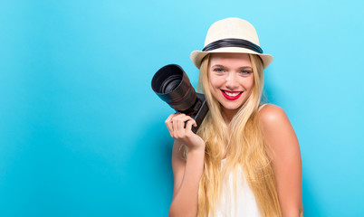Young woman comparing professional camera on a solid background