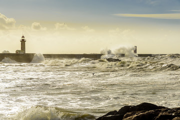 Landscape seascape lighthouse battered by huge waves on Atlantic Ocean with blue green skies and...