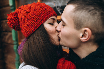Portrait happy young couple in love kissing at winter day in knitted clothes