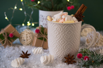 Hot chocolate in a white cup with marshmallows and Christmas gifts on the bright light background. Christmas drink.
