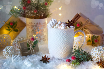 Hot chocolate in a white cup with marshmallows and Christmas gifts on the bright light background. Christmas drink.