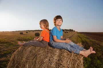 Naklejka na ściany i meble 2 boys in a haystack in the field