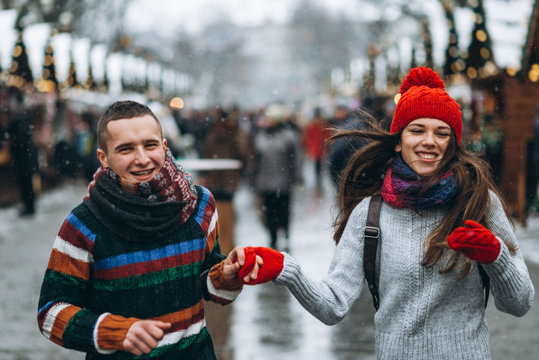 Young happy couple in knitted clothes having fun in winter city