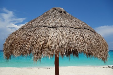 Fototapeta na wymiar A palapa thatched palm tree sun umbrella on the beach in Cancun, Mexico