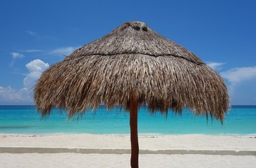 A palapa thatched palm tree sun umbrella on the beach in Cancun, Mexico