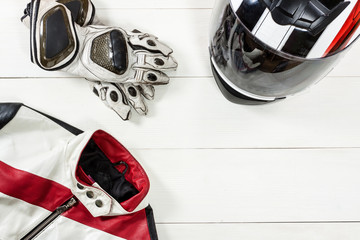 View of motorcycle rider accessories placed on white wooden table.