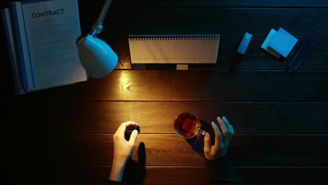 A man is sitting at an office desk and using a phone.