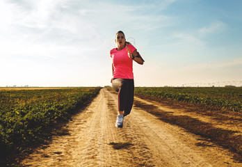 Athletic woman running on rural road.