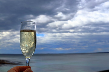 Glass of Champagne with cloudy sky at Hyams beach, Australia