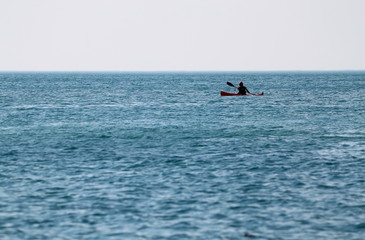 Silhouette of man in kayak on quiet sea under the midday summer sun. Sport Training