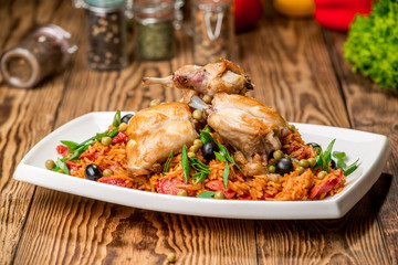 Plate with roasted rabbit leg and vegetable garnish.