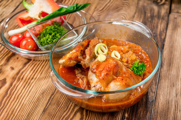 Roasted rabbit with herbs, tomato sauce and glass of wine on a plate.
