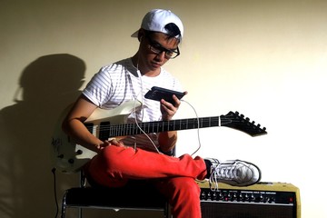 Teen with an electric guitar using a smartphone
