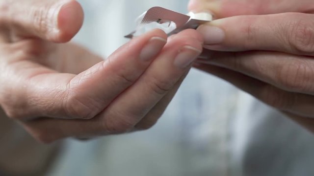Woman hands pressing pill out of plastic blister, medication, food supplement