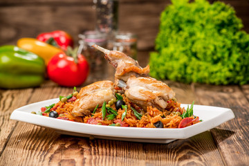 Plate with roasted rabbit leg and vegetable garnish.