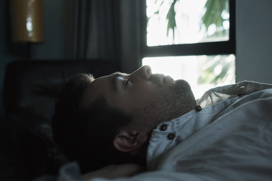 Portrait Of A Young Caucasian Man From Above Sleeping In A Dark Bed.