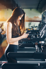 Obraz na płótnie Canvas Asian woman exercising in the gym, Young woman workout in fitness for her healthy and office girl lifestyle. She use mobile phone while excercising.