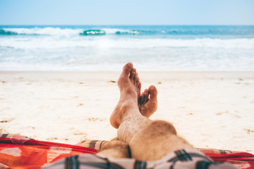 Mans feet men relaxing on the beach on a deckchair.