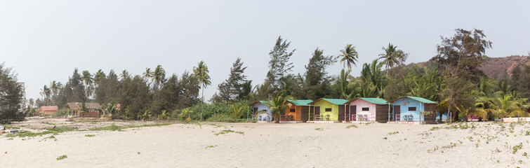 Fototapeta na wymiar Tropical paradise is a sandy beach with colorful bungalows.