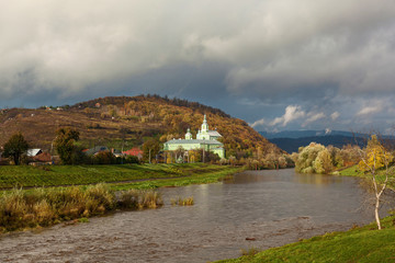 Fototapeta na wymiar monastery on the bank of the river on a cloudy day, Orthodox churches and manastyrs in captive Ukraine