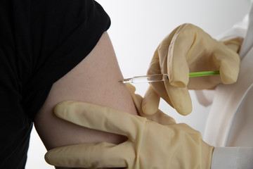 Close up of a female doctor or nurse giving an injection or vaccine to a male patient