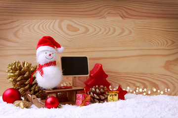 Obraz na płótnie Canvas Snowman with Christmas gifts and advertising blackboard.