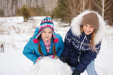 Fototapeta na wymiar two female friends building a snowman