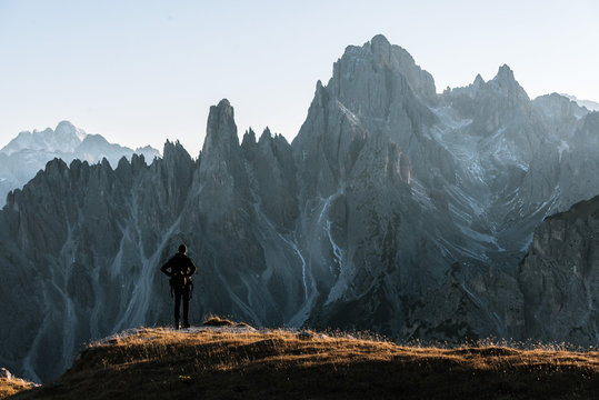 Young adult male standing and taking in the view in front of the dolomites mountains in italy