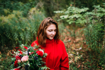 Beautiful young woman with rustic flowers. Happy girl smiling and holding bouquet outdoors. Autumn portrait of female in park.