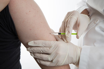 Close up of a female doctor or nurse giving an injection or vaccine to a male patient