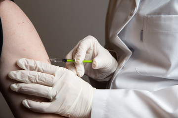 Close up of a female doctor or nurse giving an injection or vaccine to a male patient