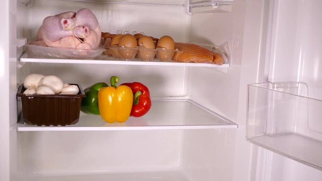 Timelapse of a fridge being stocked with fresh provisions.