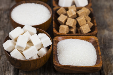 Six bowls of sugar  on a wooden background