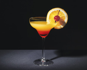 Glass with tasty exotic cocktail on black background