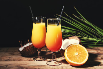 Glasses with tasty exotic cocktail on table against black background