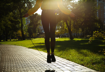 Sporty young woman jumping rope in park