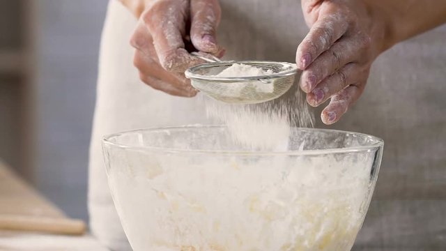 Hostess sifting extra class flour through sieve preparing tasty aromatic pies