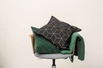 Armchair with patterned pillows and blanket on light background