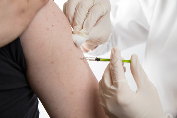 Close up of a female doctor or nurse giving an injection or vaccine to a male patient