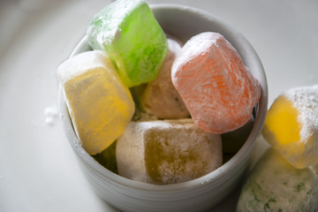 Colorful turquish delight confections, macro, white background. Cubes of variety of lokum sweets, dusted with sugar, closeup.