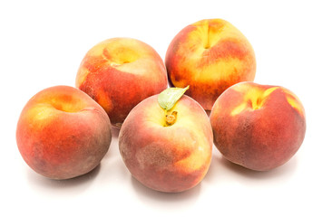 Group of five whole peaches, one with green leaf, isolated on white background.