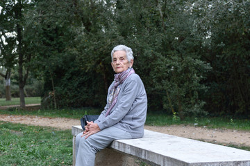Fototapeta premium senior woman sitting alone on a bench in a park