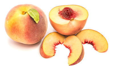 Group of peaches, whole with a green leaf, one half with a stone, isolated on white background.