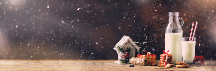 Christmas dark background with snow and bokeh, copy space. Banner. Bottle, glass with milk for...