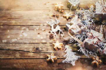 Christmas wreath with ginger cookies, silver stars, cones, hazelnut, anise, tape, ribbon, snowflakes, reindeer. Top view, copy space, light bokeh, snow effect, toned