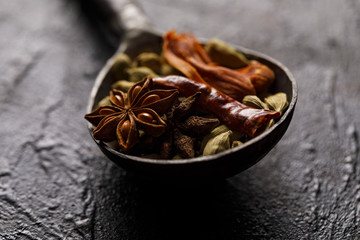 Indian Spices in a vintage spoon. On a black background.
