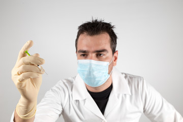 Doctor with syringe ready to give a vaccine injection. Young man in doctor outfit with a syringe, looking threatening.