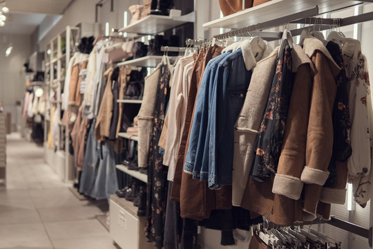 women's dresses and jacket on hangers in a retail shop.