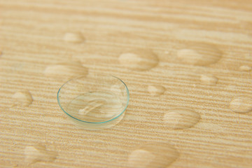 Contact lenses for eyes with drops of solution on a wooden table